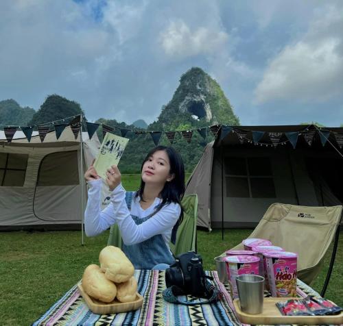 a woman sitting at a picnic table with a book at Camping Núi Thủng ở Cao Bằng in Cao Bằng
