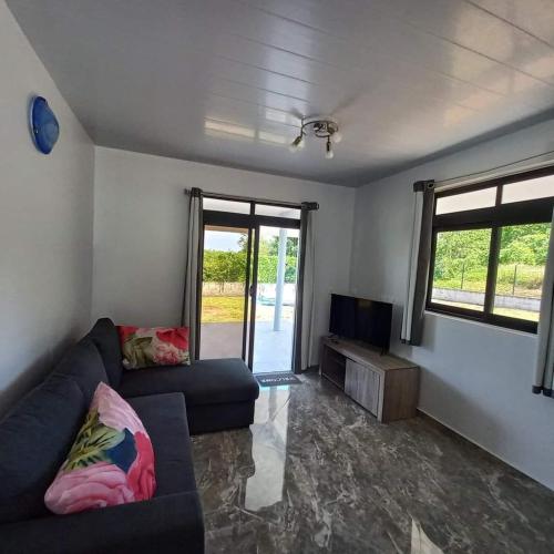 ein Wohnzimmer mit einem Sofa und einem Flachbild-TV in der Unterkunft Vaimiti Lodge in Teahupoo
