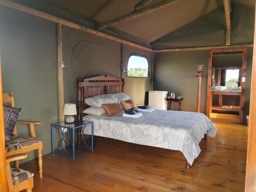 een slaapkamer met een bed en een stoel erin bij Hillcrest Lodge Tents - Nelanga in Plettenbergbaai