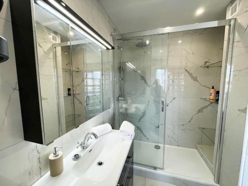 een witte badkamer met een wastafel en een douche bij Le Panoramique Luxe Centre-Ville in Clermont-Ferrand