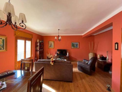 sala de estar con paredes de color naranja y sofá en El refugio de Izan, en Mora de Rubielos