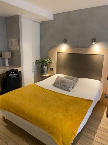 a bedroom with a large bed with a yellow blanket at Hôtel La Glycine in Bénouville
