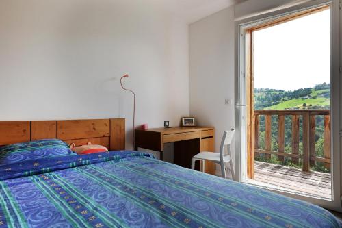 a bedroom with a bed and a desk and a window at La Bergerie du Pré de l'Orme - Avec vue montagne in La Bresse