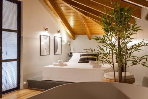 um quarto com uma cama branca e uma planta em Zerania Suites in Ilha de Rhodes