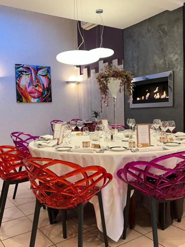 a dining room with a table with red chairs at Hôtel Bien Être La Glycine in Bénouville