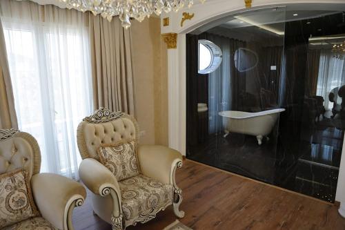 ein Badezimmer mit einem Stuhl, einer Badewanne und einem Kronleuchter in der Unterkunft Hotel Eiffel in Tirana