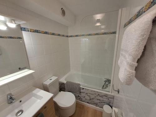 a white bathroom with a tub and a toilet and a sink at Mazet T2 - Domaine de la Pinède - Piscine Chauffée in Le Lavandou