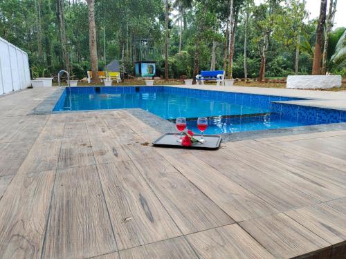 two glasses of wine sitting next to a swimming pool at Paddyfield Inn in Mananthavady