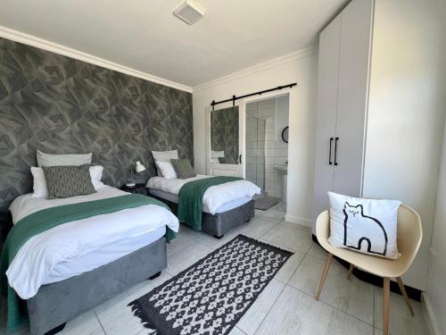 Un dormitorio con 2 camas y una silla. en On the Main en Walvis Bay