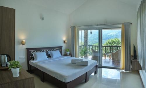 a bedroom with a large bed and a balcony at Clouds View Nature Resort in Koroth