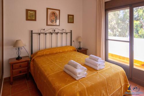 1 dormitorio con 1 cama con toallas en El Velero Sotillo con Piscina, en San José