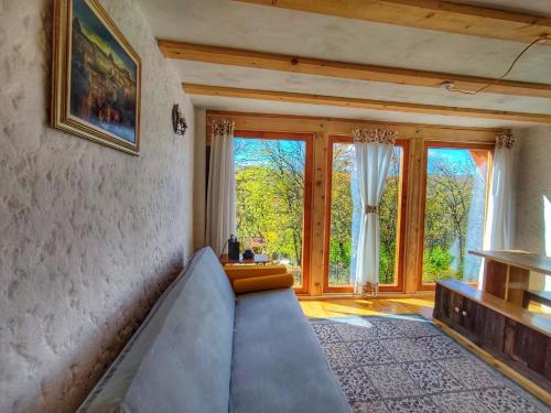 a living room with a couch and some windows at La sat - Blândă Mărie in Bertea