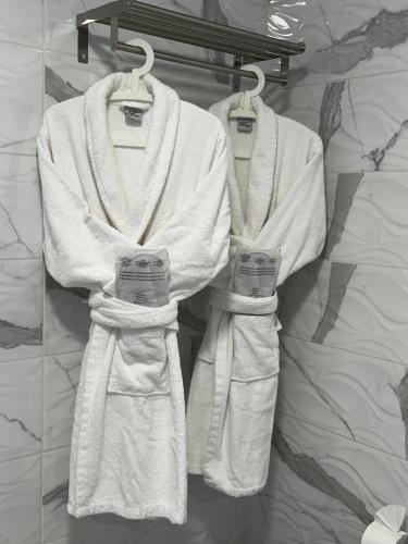 three white towels hanging on a rack in a bathroom at Paradise Resort - FKK Swinger & Nudist Couples Only in Maspalomas