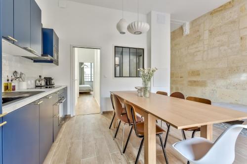 a kitchen and dining room with a wooden table and chairs at Nocnoc - L'Oli 102m2 avec patio et jacuzzi in Bordeaux