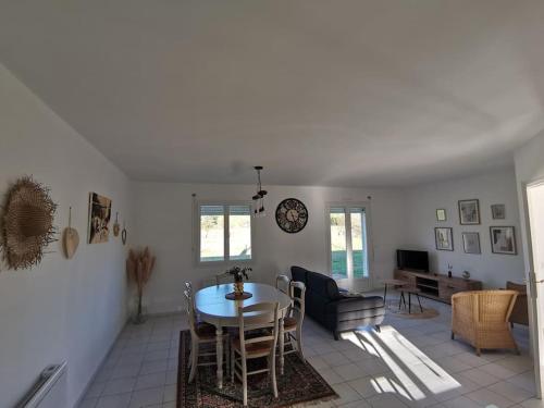 a dining room and living room with a table and chairs at La Maison du Bagas, 7pers in Vielmur