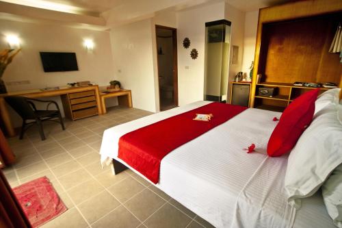 a bedroom with a large bed with red sheets and a desk at Asia Grand View Hotel in Coron