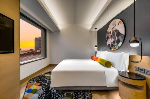 a bedroom with a white bed and a large window at Hotel Indigo Taipei North by IHG in Taipei