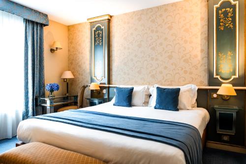 a hotel room with a large bed with blue pillows at Villa Beaumarchais in Paris