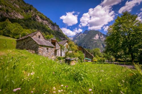 an old stone house on a hill with mountains in the background at Casa Mima Chalets in Gerra Verzasca