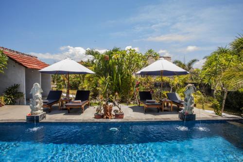 Bagus Dream Beach Villa Lembongan في نوسا ليمبونغان: مسبح مع كراسي ومظلات بجوار منزل