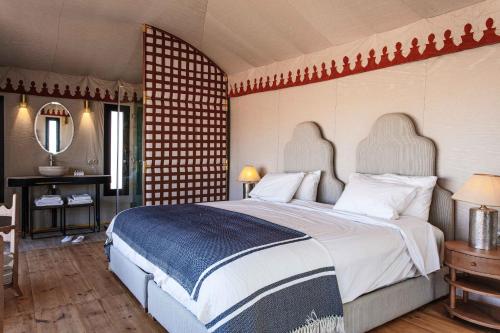a bedroom with a large bed and a mirror at Merzouga luxury desert camps in Merzouga