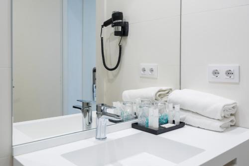 ein Bad mit einem Waschbecken und einem Spiegel in der Unterkunft Hotel Lauria in Tarragona
