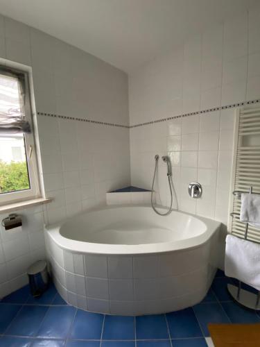 a white bath tub in a white tiled bathroom at Haus Clearwater in Bruck an der Mur