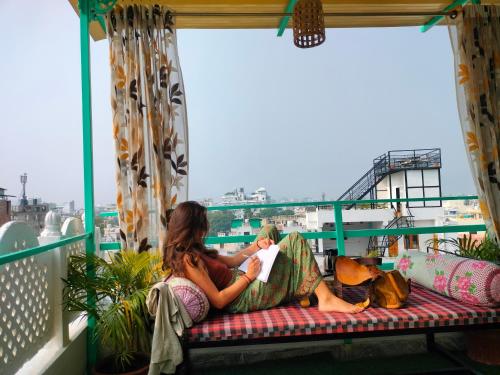Dos personas sentadas en un balcón leyendo un libro en Krishna Stay Guest House, en Udaipur
