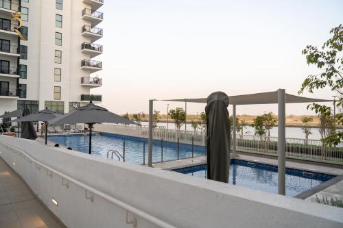 a swimming pool with umbrellas next to a building at Yas Island 2 BR Turquoise in Abu Dhabi