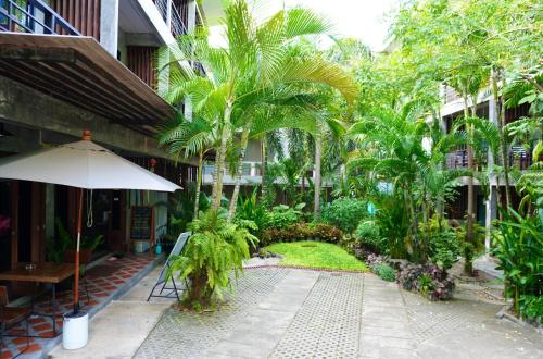 龜島的住宿－Blue Wave House，一座带遮阳伞和棕榈树的建筑的庭院