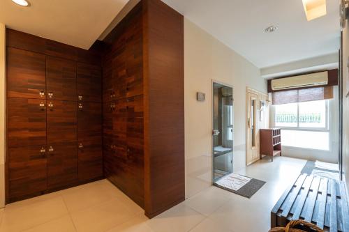 a dressing room with wooden cabinets and a bench at Kantary Hills Hotel, Chiang Mai in Chiang Mai