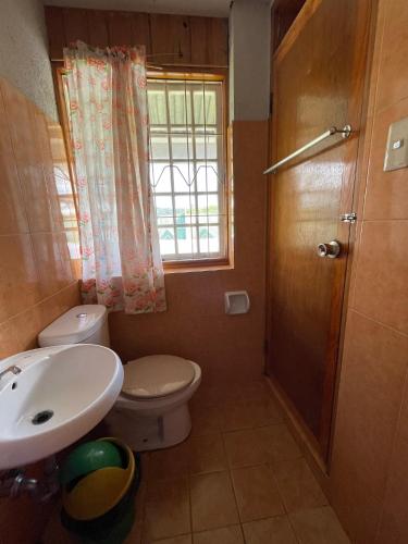 a bathroom with a sink and a toilet and a window at Saint Joseph Inn in Sagada