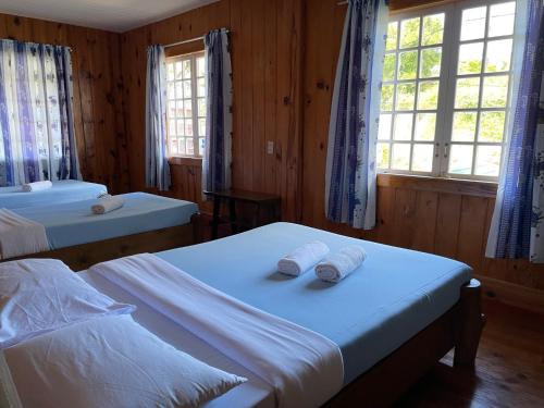 a bedroom with two beds and two windows at Saint Joseph Inn in Sagada