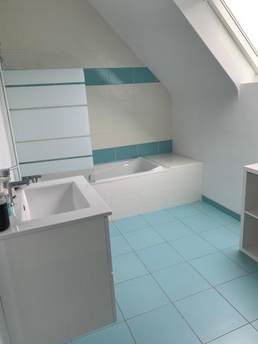 La salle de bains est pourvue d'un lavabo et d'une baignoire. dans l'établissement Maison Jardin De La Baie, à Douarnenez
