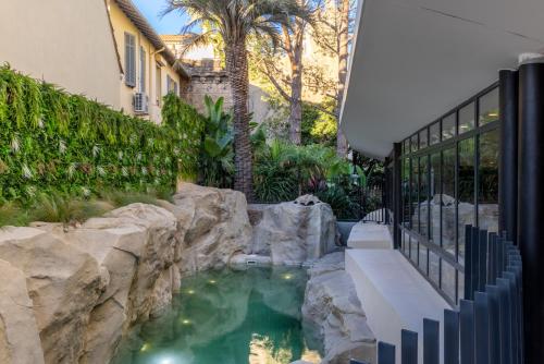 - une piscine au milieu d'une cour avec des rochers dans l'établissement Staybridge Suites - Cannes Centre, an IHG Hotel, à Cannes