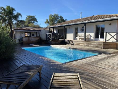 - une piscine sur une terrasse en bois à côté d'une maison dans l'établissement VILLA PALOMA maison moderne piscine chauffée, à La Teste-de-Buch