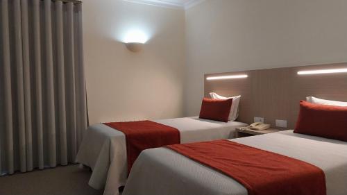 a hotel room with two beds with red sheets at Hotel Santa Maria in Alcobaça