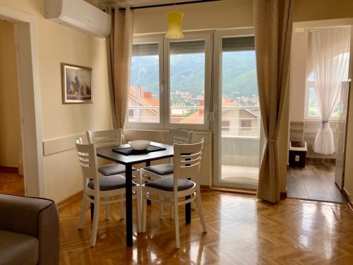 Un comedor con mesa y sillas y ventanas. en Apartman Ivanka, en Soko Banja