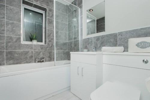a white bathroom with a tub and a sink at Hurrell House in Boreham
