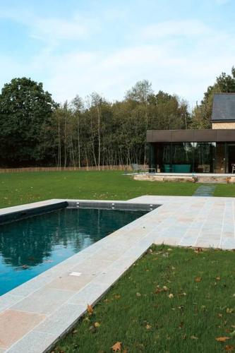 une piscine dans un parc avec un bâtiment dans l'établissement Magnifique ferme rénovée, à Plélan-le-Petit