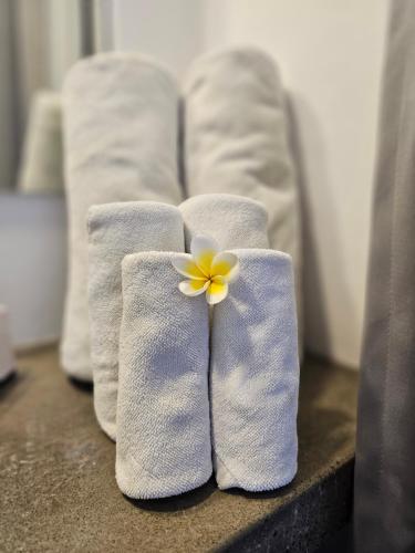 Chandi Hotel Ubud في أوبود: ثلاث مناشف بيضاء عليها وردة صفراء