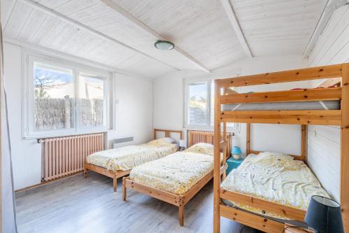 1 Schlafzimmer mit 2 Etagenbetten und 2 Fenstern in der Unterkunft Appartement 10 pers à 50m plage in Barbâtre