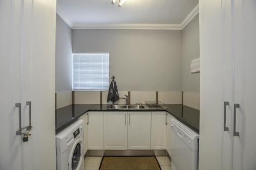 a white kitchen with a sink and a washing machine at Apartment 6 in Yzerfontein