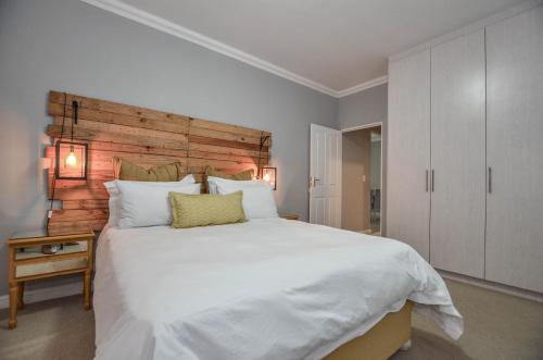 a bedroom with a large white bed with a wooden headboard at Apartment 6 in Yzerfontein