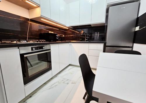 een keuken met witte kasten en een tafel met stoelen bij Luxury Apartment in Boekarest