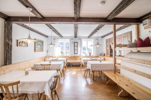 un restaurante con mesas y sillas blancas y ventanas en Rieplhof, en Vipiteno