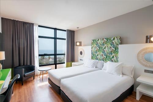 Habitación de hotel con cama y ventana grande en Vincci Málaga en Málaga