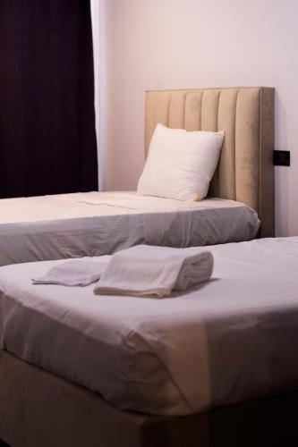 two beds with white sheets and a pillow at HASS Boutique Hotel in Gostivar