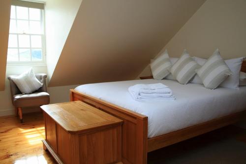 een slaapkamer met een bed met witte lakens en een stoel bij Bertrand's Cottage in Jamestown