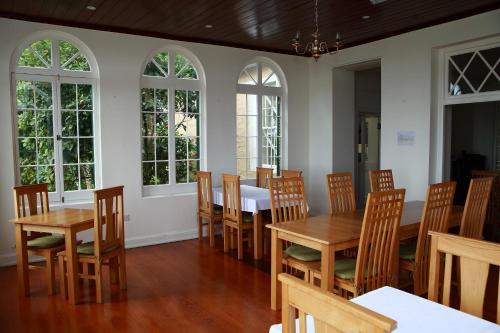 een eetkamer met tafels, stoelen en ramen bij Bertrand's Cottage in Jamestown